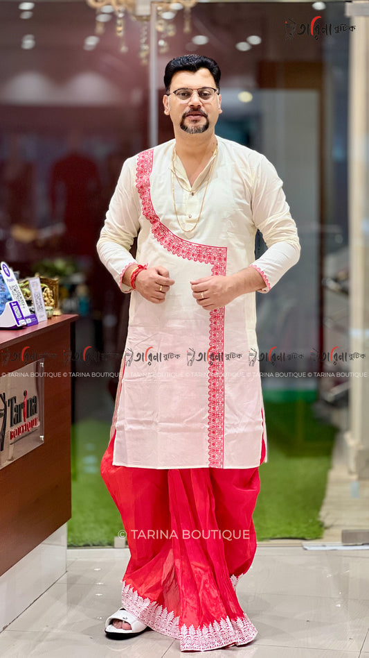 Man wearing a traditional outfit with a white kurta and red saree in a store setting.